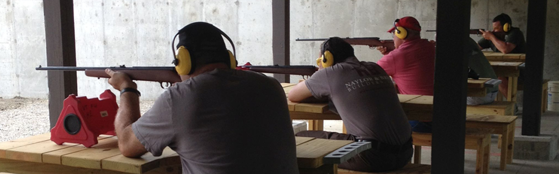 several people aiming firearms at shooting benches