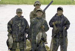 Four young waterfowl hunters holding bagged ducks