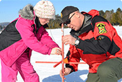 warden helping a young girl ice fish