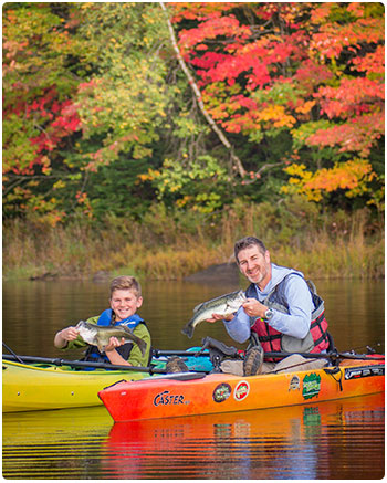 two anglers in kayaks with fish and fall colors