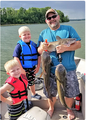 Father with two sons showing off their catfish catch