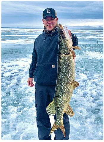 angler with nice pike caught through the ice