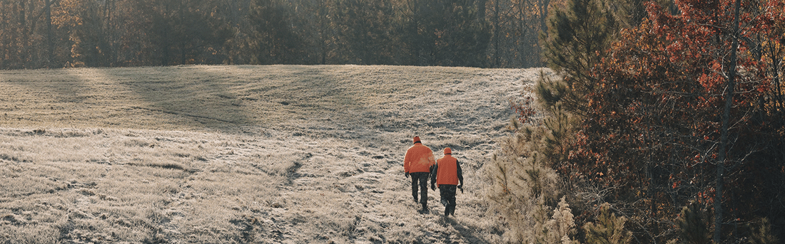 two hunters walking in a field
