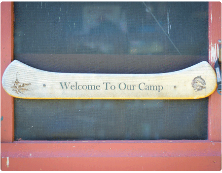 screen door with a carved sign saying welcome to our camp