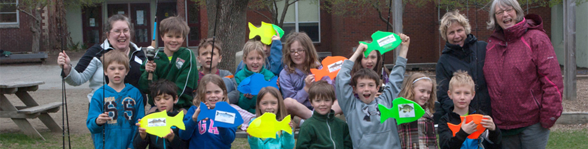 Kids at a fishing event holding rods and paper fish cutouts