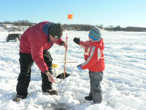 A man and child use baitfish for ice fishing