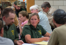 A candid shot of a couple fish and wildlife staff and constituents discussing regulations changes at a table during a previous public hearing.