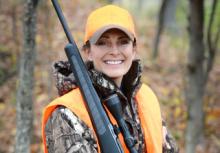smiling women hunter with rifle and orange hat and vest